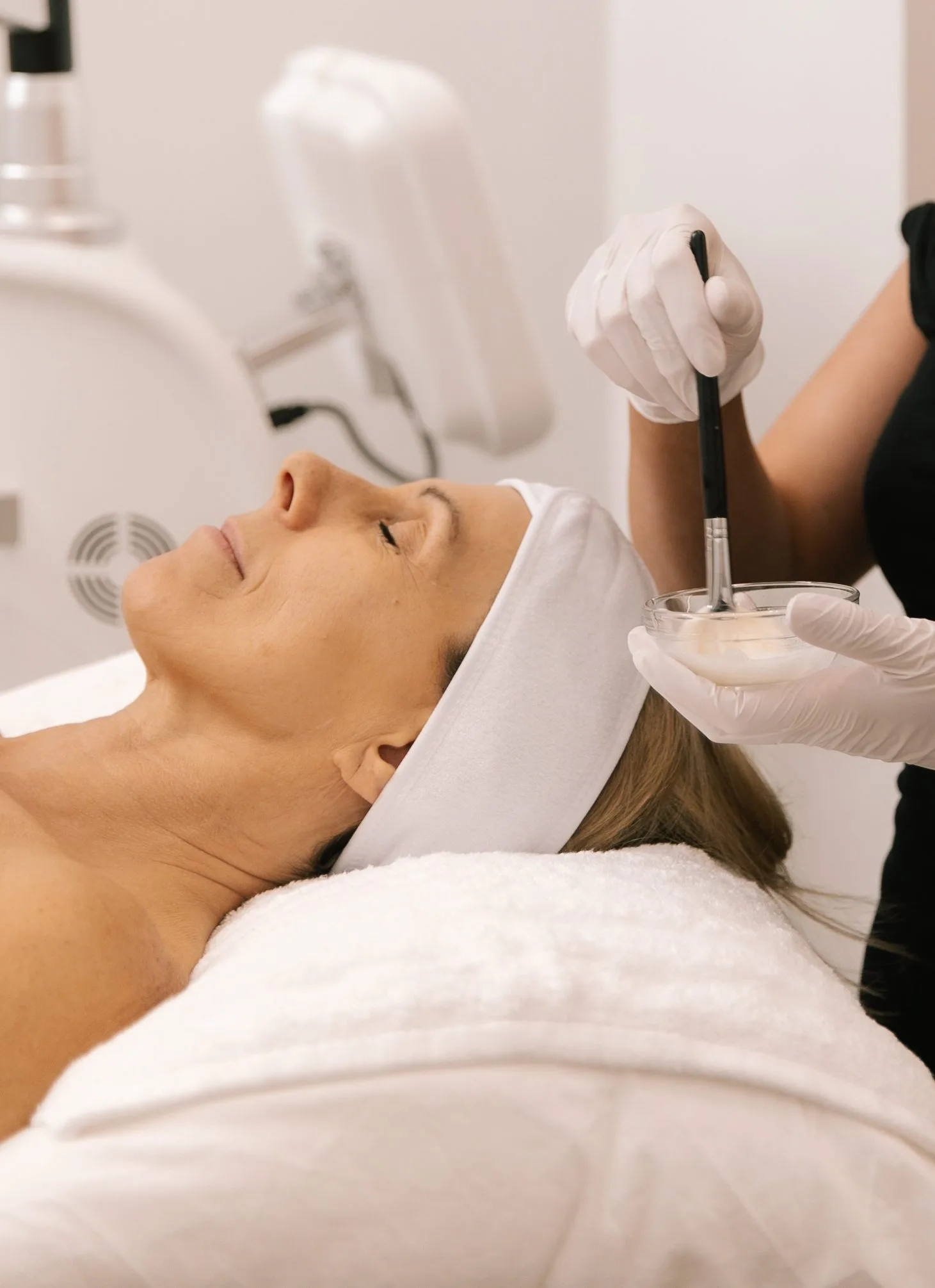 Dermal clinician preparing to brush a treatment serum onto a clients face during a Signature Plump and Glow facial at Plump Aesthetic Clinic South Yarra