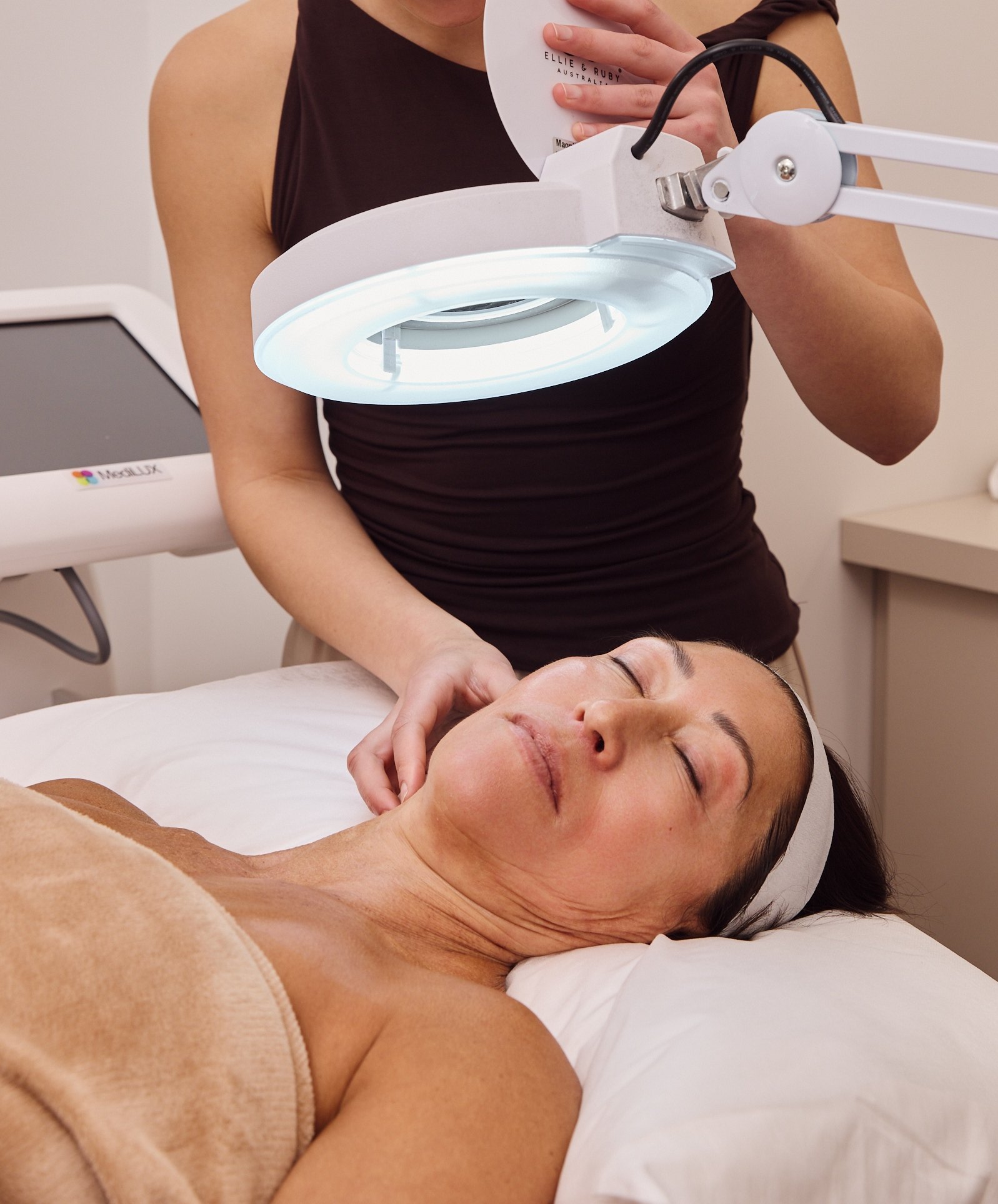 Dermal clinician assessing a clients skin under a magnifying lamp during a skin consultation at Plump Aesthetic Clinic South Yarra