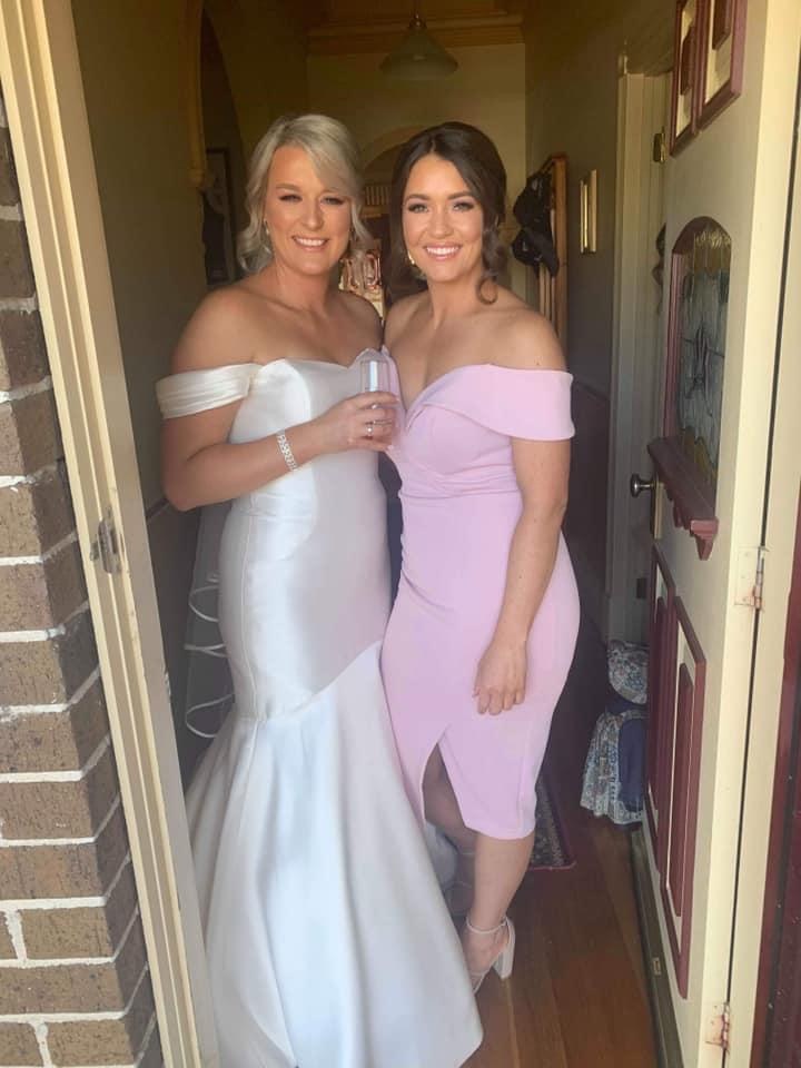 Bride in a white gown with a guest in a blush dress in a doorway